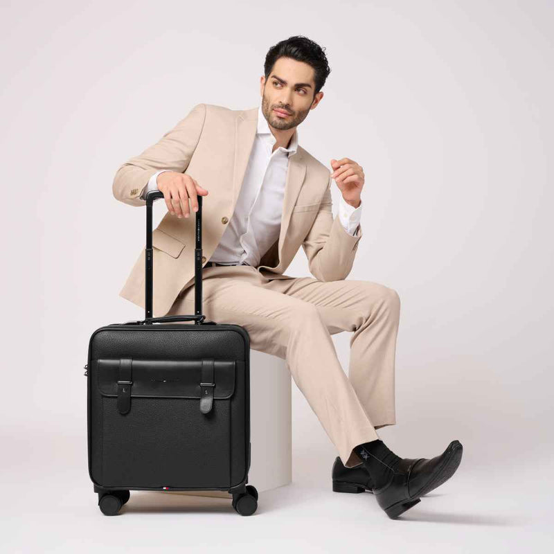 Tommy Hilfiger Lincoln Hardshell Overnighter Cabin Trolley in Black — lifestyle shot, seated model