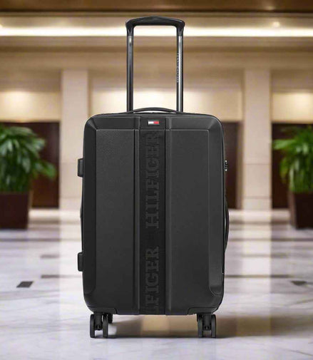 Tommy Hilfiger Arbor Polycarbonate Trolley Bag in Black — lifestyle shot in hotel lobby