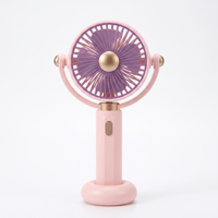 LS rechargeable handheld mini fan in pink with purple blades and antique-gold centre cap, standing upright on its round base